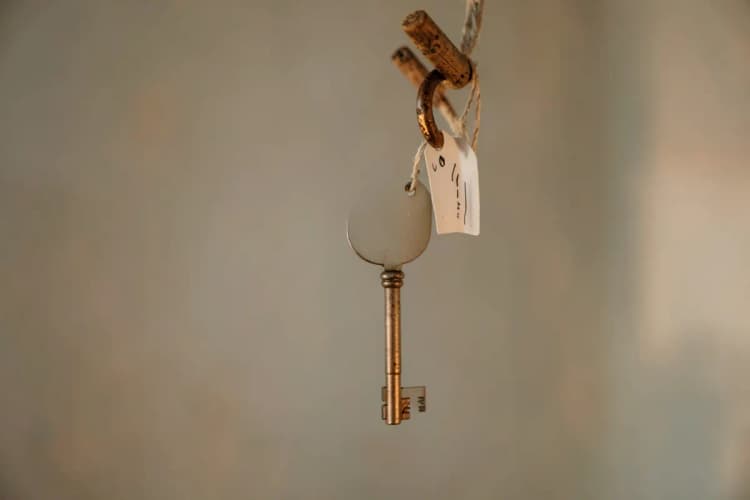 Chave de casa antiga com etiqueta de preço pendurada em gancho de madeira