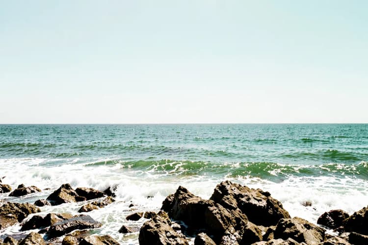 Ondas do mar batendo em rochas na costa com espuma branca