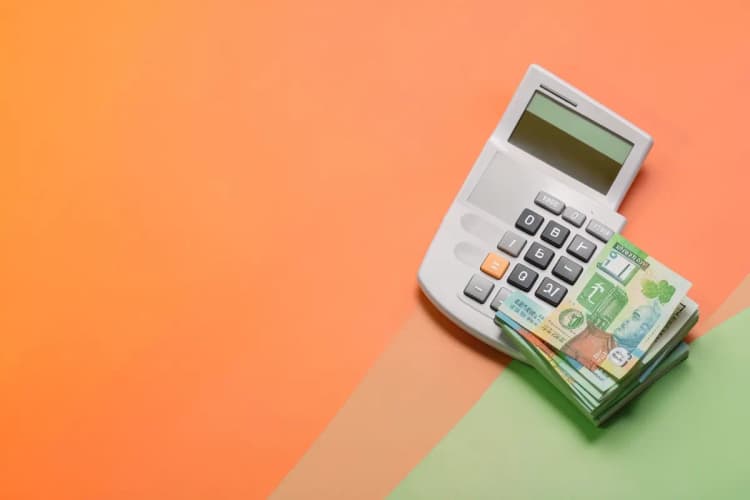 Calculadora financeira e notas de dinheiro organizadas sobre um plano de trabalho limpo