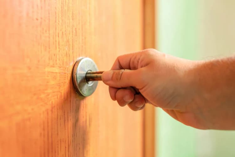 Uma pessoa colocando uma chave em uma fechadura de porta de madeira.