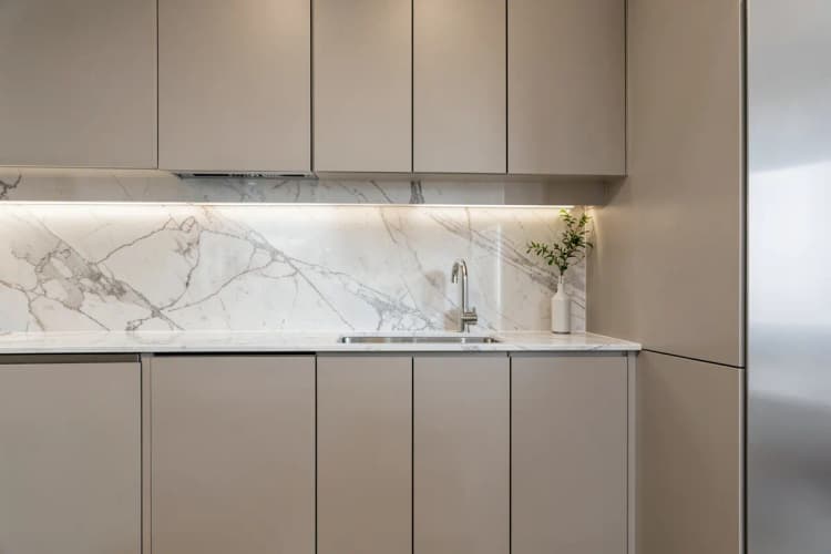 Cozinha gourmet com armários planejados, bancada de mármore e eletrodomésticos embutidos de aço inoxidável.